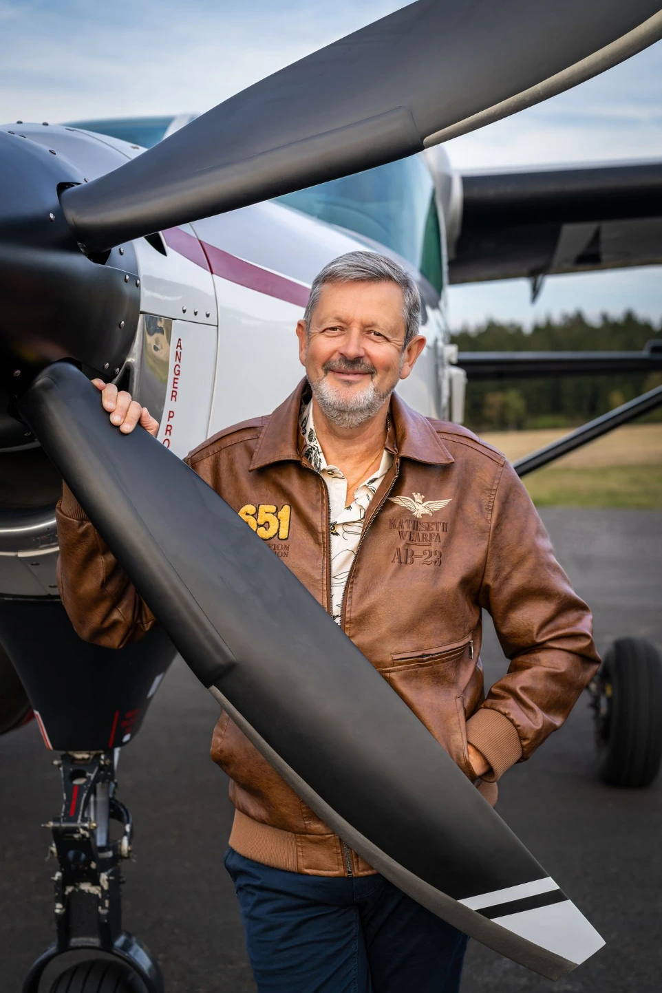 Professionelles Porträt eines Piloten vor seinem Flugzeug, das Expertise, Ambition und Souveränität vermittelt.